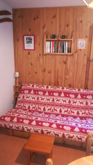 A wooden-paneled room with a bed, a shelf with books, a framed certificate, and a no-smoking sign. - Summer and Winter Vacations in Savoie (Aréches)