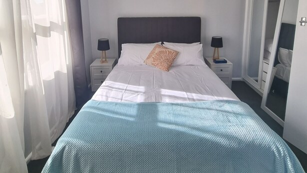 Una camera da letto con un letto, una ventola a soffitto, un comodino con una lampada e un armadio.