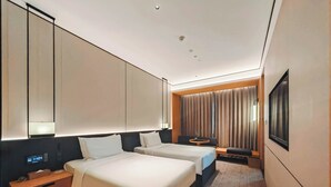 Habitación de hotel con dos camas, una mesita de noche, un televisor y un espejo grande.