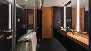 A modern bathroom with a glass shower enclosure, a wooden vanity, and a large mirror.
