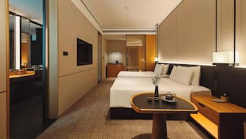 A hotel room with a bed, bedside table, lamp, and a small table with a vase and teapot.