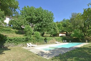 A swimming pool with lounge chairs, surrounded by greenery and a stone wall. - Large holiday home with a swimming pool in Le Var (Collobrieres)