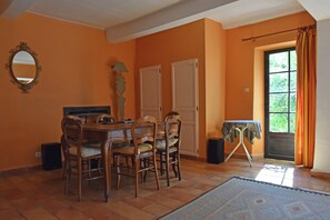 A dining area with a wooden table and chairs, a mirror, and a window with curtains. - Large holiday home with a swimming pool in Le Var (Collobrieres)