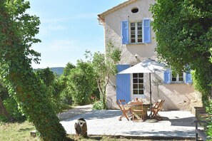 En rustik bygning med terrasse, udendørs siddepladser og et lille bord.