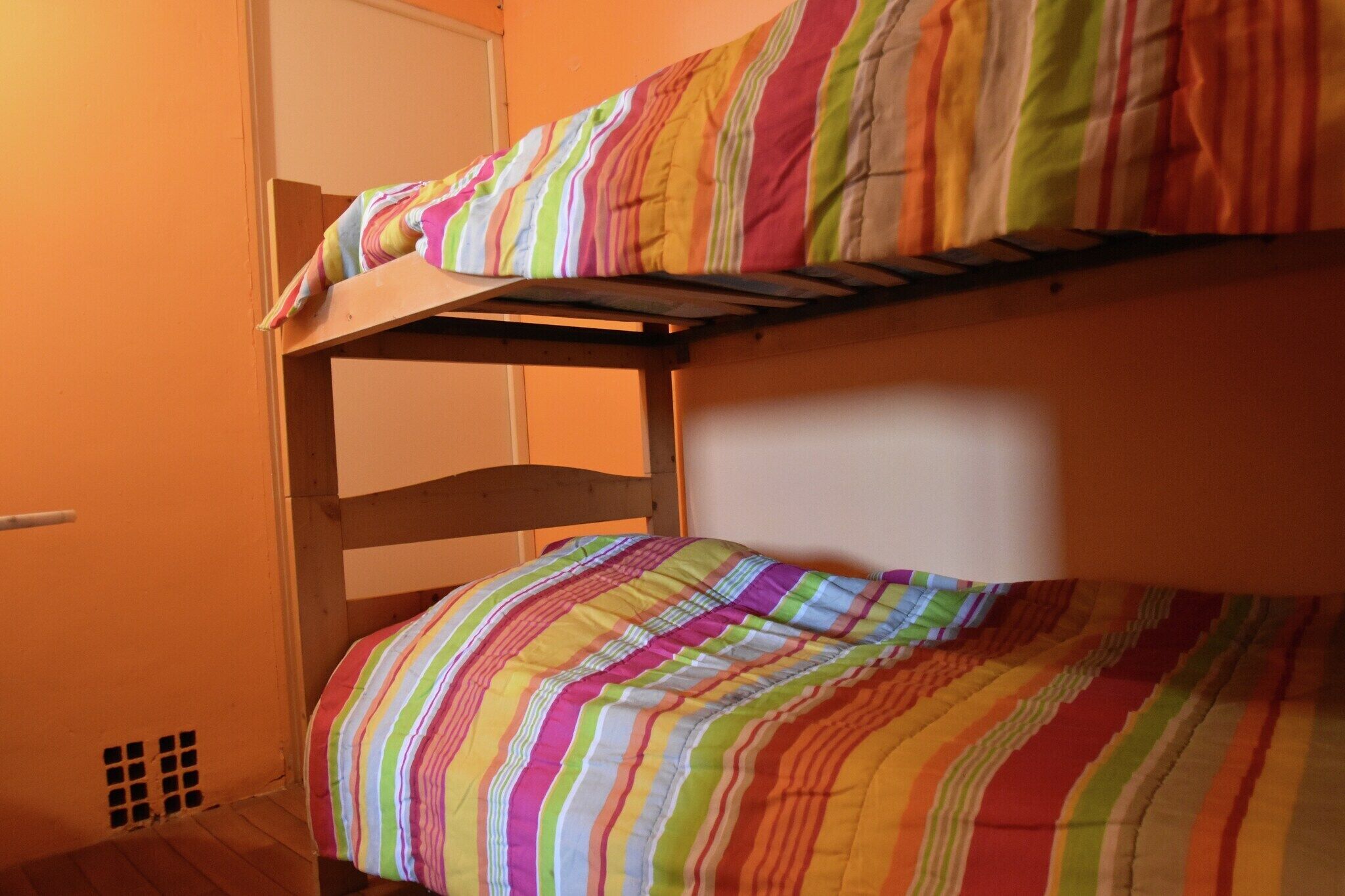 Un lit superposé avec une couverture rayée aux couleurs vives.