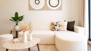 Ein modernes Wohnzimmer mit einer Eckcouch, einem runden Couchtisch und einem Blumentopf.
