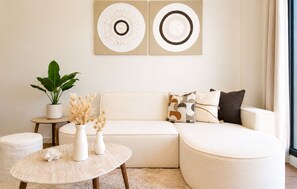 Ein modernes Wohnzimmer mit einer Eckcouch, einem runden Couchtisch und einem Blumentopf.