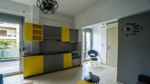 A modern kitchen with yellow and grey cabinets, a black countertop, and a wall clock. - Urban Studios (Rethymno)