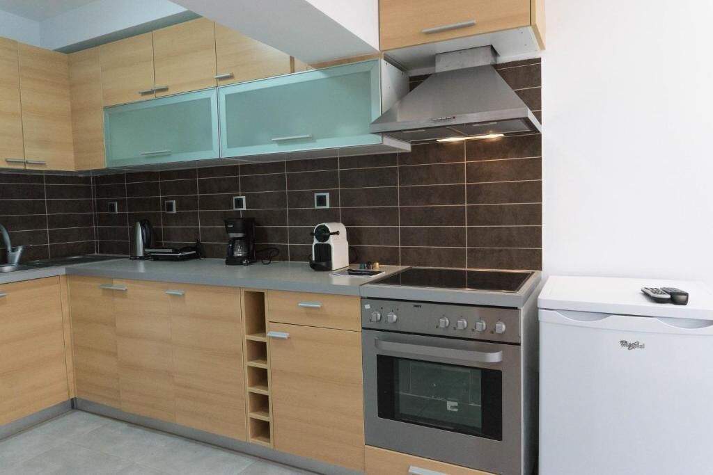 Una cocina moderna con armarios de madera, horno empotrado, cafetera y refrigerador.