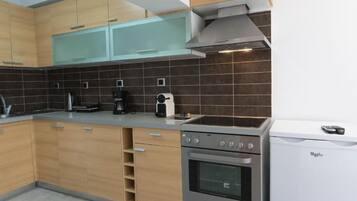 Una cocina moderna con armarios de madera, horno empotrado, cafetera y refrigerador.