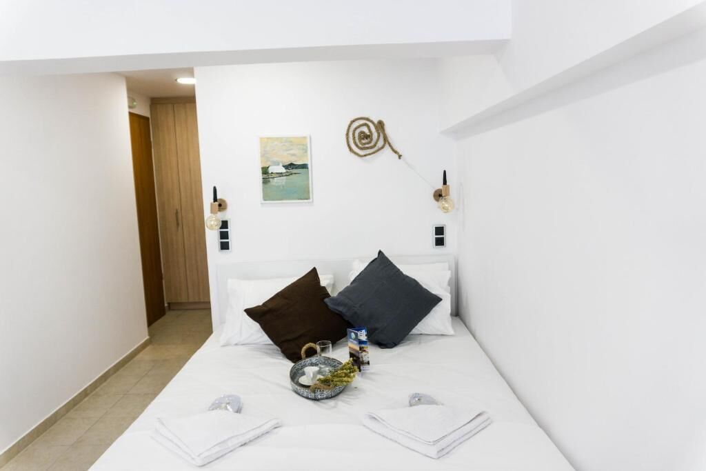 Habitación de hotel con cama, almohadas, mesita de noche, lámpara de pared y un cuadro.
