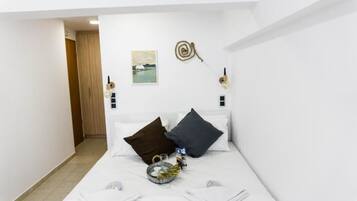 Habitación de hotel con cama, almohadas, mesita de noche, lámpara de pared y un cuadro.