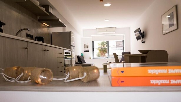 A modern kitchen with a dining area, a sofa, and a window with a view. - Urban Studios (Rethymno)