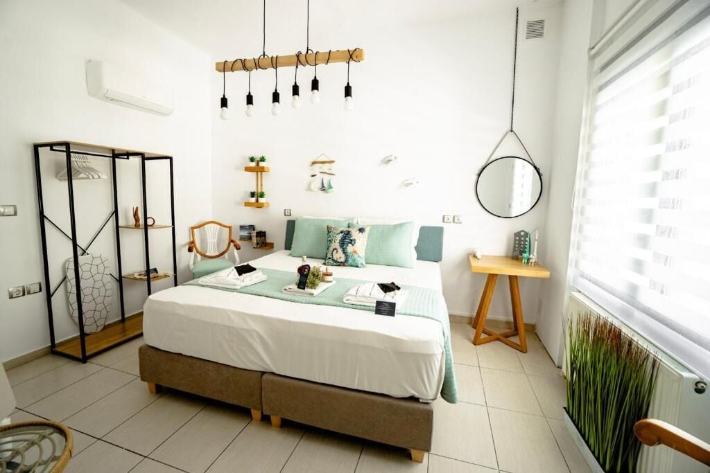 A modern bedroom with a bed, bedside table, hanging light fixture, and a window with blinds.