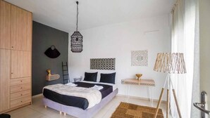 A bedroom with a bed, wardrobe, bedside table, lamp, and wall decorations. - Urban Studios (Rethymno)