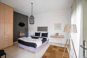 Un dormitorio con cama, armario, mesita de noche, lámpara y adornos en la pared.
