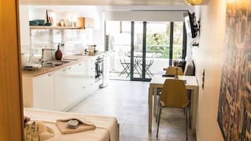 Cocina compacta con comedor, cama y vista al exterior.