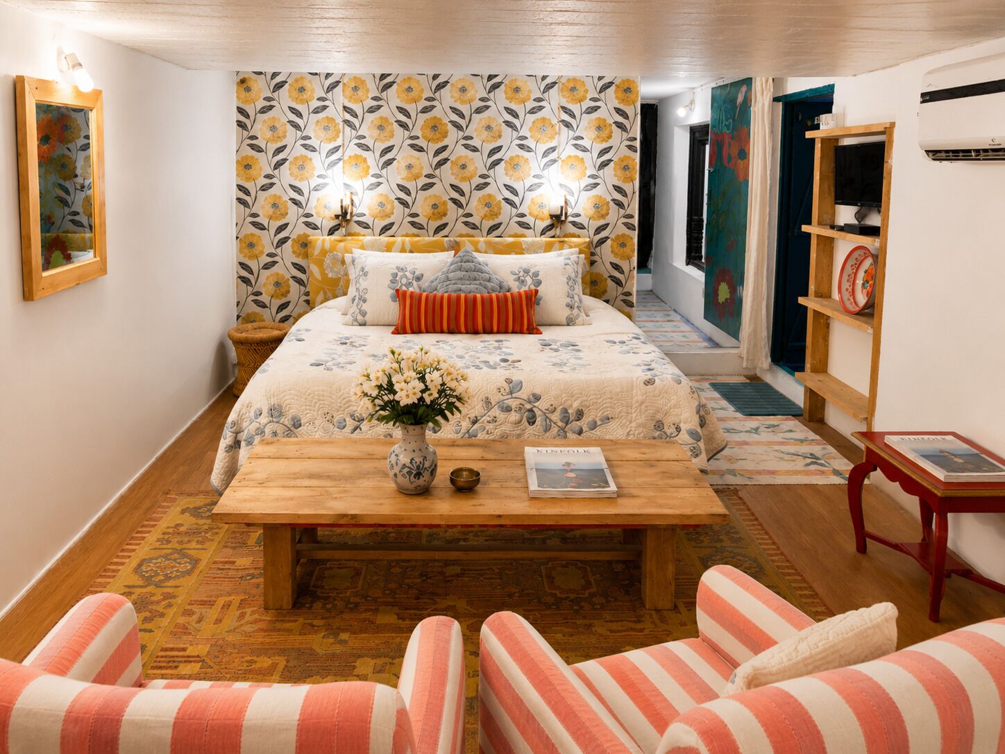 Un dormitorio con cama, mesitas de noche, una mesita auxiliar, una mesa de centro de madera y una silla.