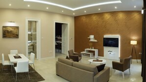 Un salon moderne comprenant un canapé, une table basse, un téléviseur et un coin repas avec des chaises et une table.