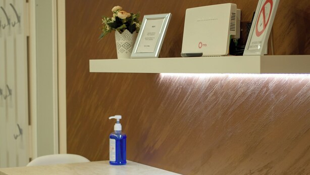 Un comptoir d’accueil avec une chaise blanche, une bouteille bleue et un certificat encadré accroché au mur.