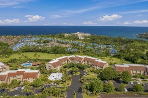 A resort with multiple buildings, a central pool, and a view of the ocean. - Fully Renovated Luxury Condo | Ocean Views + AC (Kailua-Kona)