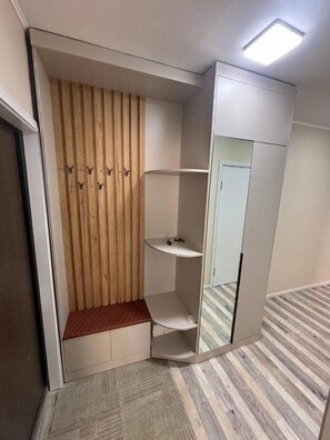 Une chambre d’angle dotée d’une armoire intégrée, d’un banc et d’une petite étagère.