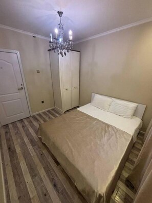 A bedroom with a bed, a wardrobe, a chandelier, and wooden flooring. - Superb 3-bedroom apartment in Ulaanbaatar for your stay (Ulaanbaatar)