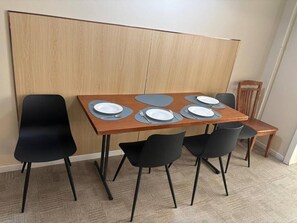 A dining area with a wooden table, black chairs, and a partition wall. - Superb 3-bedroom apartment in Ulaanbaatar for your stay (Ulaanbaatar)