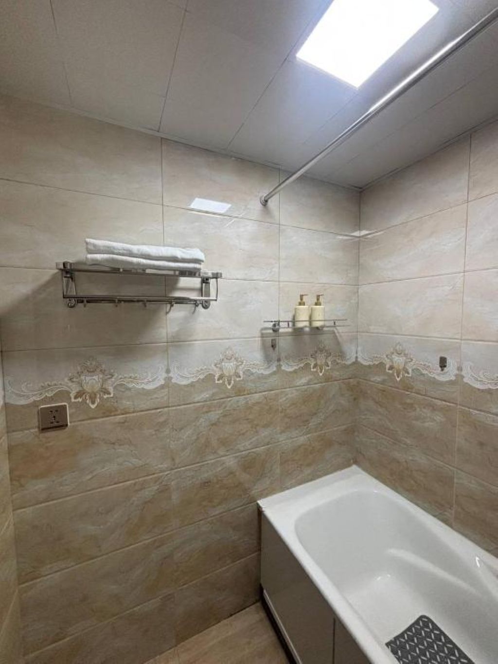 A bathroom with a bathtub, a towel rack, and a shelf with toiletries.