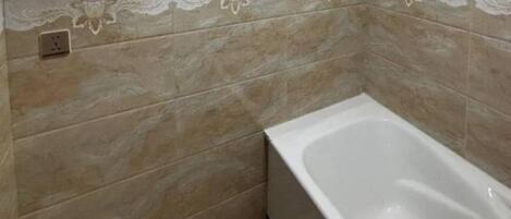 A bathroom with a bathtub, a towel rack, and a shelf with toiletries.