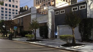 Rua residencial com casas, porta de garagem e placa de rua.