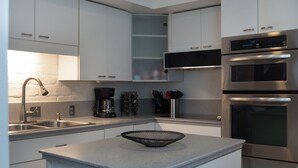Uma cozinha moderna com eletrodomésticos de aço inoxidável, forno embutido e cafeteira.