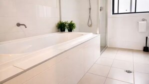 Et moderne badeværelse med badekar, brusebad og et vindue.
