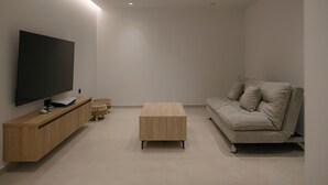 A modern living room with a flat-screen TV, wooden furniture, and a beige sofa. - Lynx Villa, Heated Pool, Walk to Shops & Dining (Rethymno)