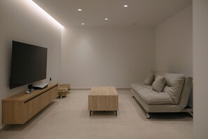 A modern living room with a flat-screen TV, wooden furniture, and a beige sofa. - Lynx Villa, Heated Pool, Walk to Shops & Dining (Rethymno)
