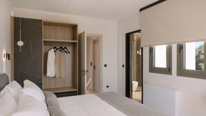 A modern bedroom with a bed, a wooden wardrobe, and a bathroom visible through an open door. - Lynx Villa, Heated Pool, Walk to Shops & Dining (Rethymno)