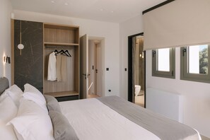 A modern bedroom with a bed, a wooden wardrobe, and a bathroom visible through an open door. - Lynx Villa, Heated Pool, Walk to Shops & Dining (Rethymno)