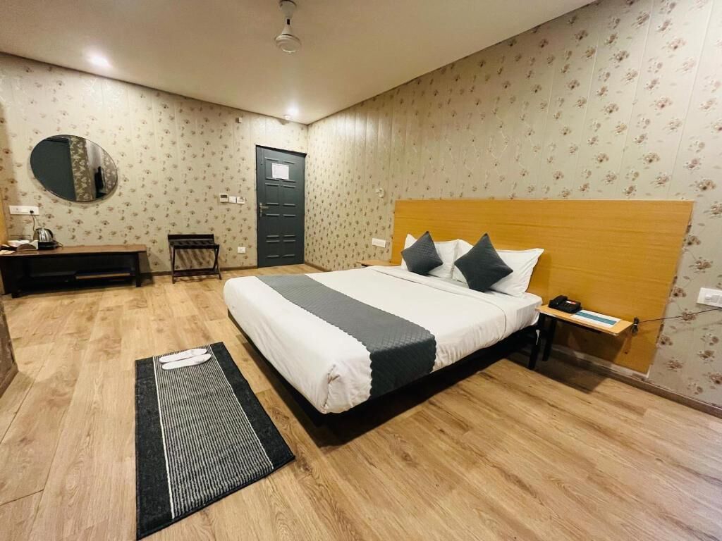 Ein Schlafzimmer mit Bett, Nachttisch, Schreibtisch, Stuhl und einem Spiegel an der Wand.