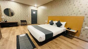 Ein Schlafzimmer mit Bett, Nachttisch, Schreibtisch, Stuhl und einem Spiegel an der Wand.