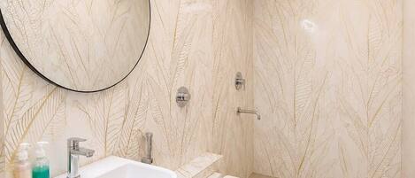 A modern bathroom with a large mirror, a sink, a toilet, and a shower.