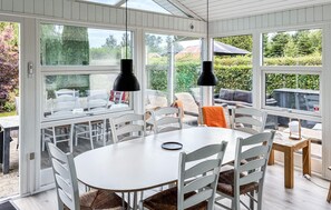 Ein Wintergarten mit Esstisch, Stühlen und Pendelleuchten.