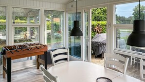 Ett rum med ett fotbollsspel, ett runt matbord och en grill utomhus.