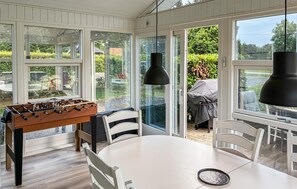 A room with a foosball table, a round dining table, and a grill outside. - 4 bedroom awesome home in Væggerløse (Væggerløse)