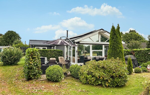 A house with a conservatory, outdoor seating, and a well-maintained garden. - 4 bedroom awesome home in Væggerløse (Væggerløse)