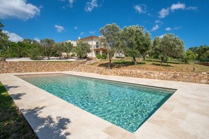 A rectangular swimming pool with clear water, surrounded by a stone wall and a stone pathway. - Villa Le Sfumature Mediterranee - Sardinia Unlimited (San Teodoro)