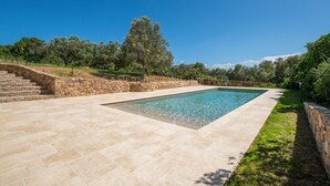 A rectangular pool with stone steps leading up to it, surrounded by a stone wall and a grassy area with trees. - Villa Le Sfumature Mediterranee - Sardinia Unlimited (San Teodoro)