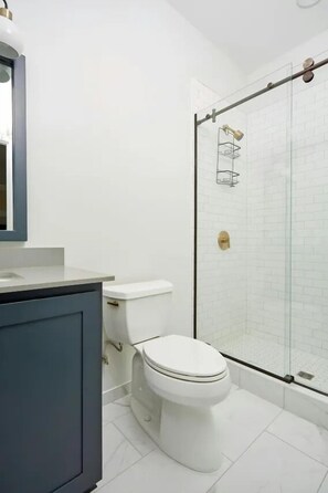 Ein modernes Badezimmer mit Toilette, Waschtisch und einer Duschkabine aus Glas.