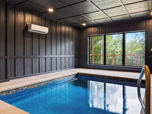 An indoor swimming pool with a view of trees through large windows. - Sleeps 20 + Indoor Pool + Game Room Near Pigeon Forge | Spurling Retreat (Sevierville)