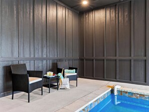 Una habitación con piscina, dos sillas de mimbre, una mesa pequeña con una bebida y un bolso con la etiqueta 'Office of Office'.