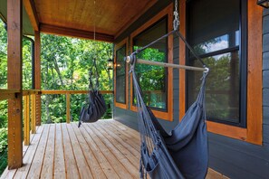 A wooden deck with a hammock and a hanging bag. - Sleeps 20 + Indoor Pool + Game Room Near Pigeon Forge | Spurling Retreat (Sevierville)